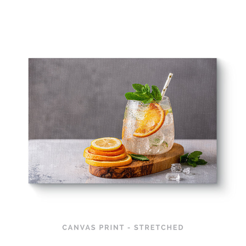 a drink with orange slices and mint on a cutting board