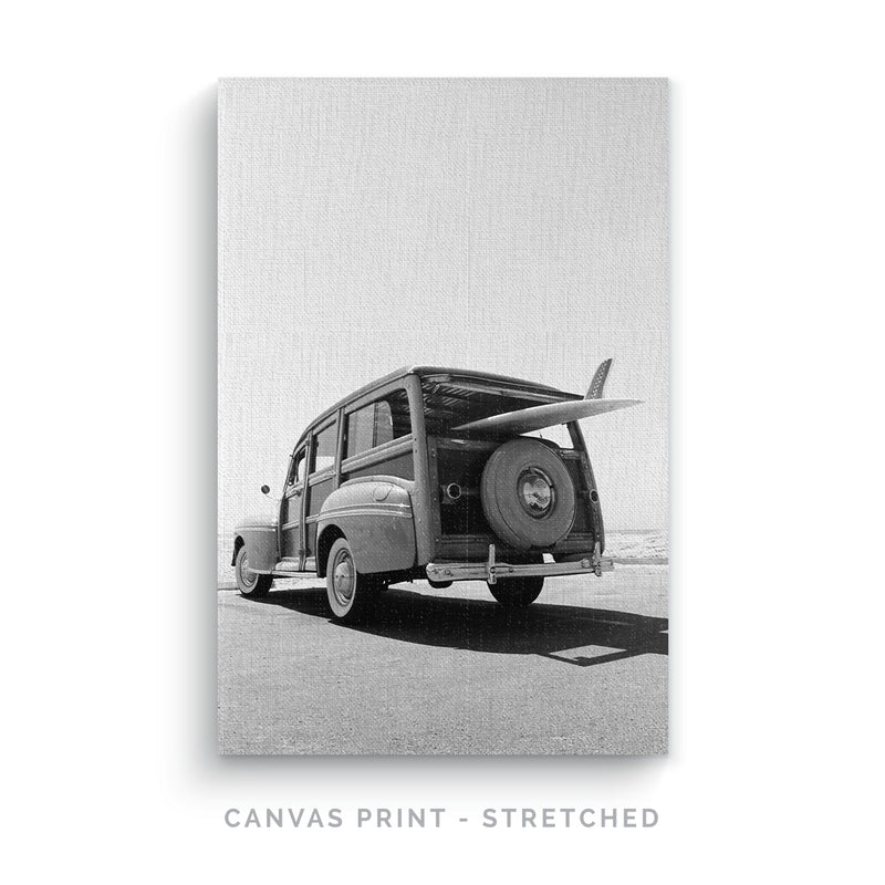 a black and white photo of an old car with a surfboard on the back
